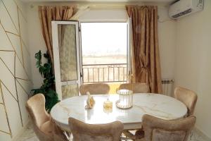 a dining room table with chairs and a large window at Golf paradis in Oran