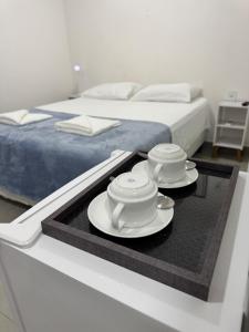 a tray with two cups and saucers on a bed at Pousada 8 Mares in Arraial do Cabo +40 photos