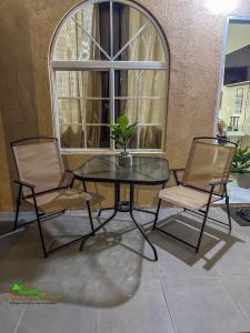 two chairs and a table with a plant on it at Phoenix Eden in Portmore +3 photos