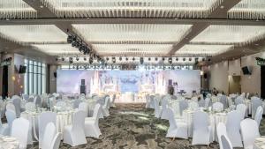 a banquet hall with white tables and chairs and a screen at Steigenberger Phnom Penh in Phnom Penh +75 photos