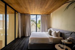 a bedroom with a large bed and a large window at Usawa Villa Nyanyi in Munggu +83 photos