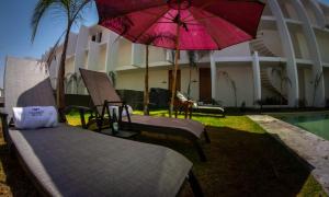 a patio with two beds and a pink umbrella at Casa Diamante Viñedos in Ezequiel Montes
