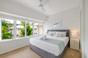a white bedroom with a large bed and a window at Balboa Apartments in Port Douglas +85 photos