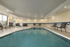 a pool in a hotel room with chairs and tables at Fairfield Inn & Suites by Marriott Springdale in Springdale