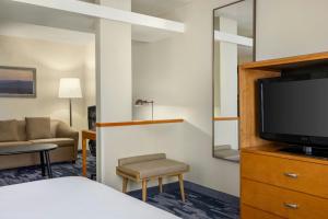 a hotel room with a bed and a flat screen tv at Fairfield Inn & Suites by Marriott Springdale in Springdale