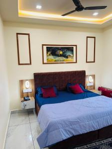 a bedroom with a large bed with blue sheets and red pillows at Norway Residency in Jagādhri +5 photos