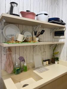 a kitchen counter with a sink and shelves with dishes at DASIG Homes1 near airport, Bayanihan Flats 1 Condominium Mactan in Pajak
