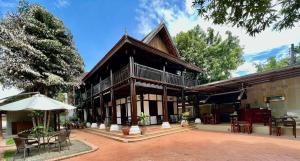 a building with an umbrella and tables and chairs at Villa Vieng Sa Vanh Hotel & Travel in Luang Prabang