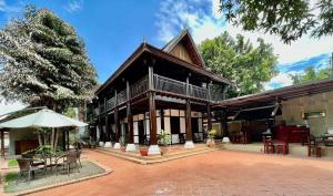 a building with a patio and a table and chairs at Villa Vieng Sa Vanh Hotel & Travel in Luang Prabang