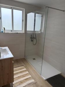 a bathroom with a glass shower with a sink at Casa Brumar Beach and Downtown on Foot in Praia da Vitória +15 photos