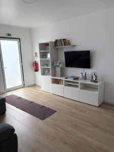 a living room with a white entertainment center with a flat screen tv at Casa Brumar Beach and Downtown on Foot in Praia da Vitória