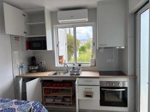 a kitchen with white cabinets and a sink and a window at Casa Brumar Beach and Downtown on Foot in Praia da Vitória