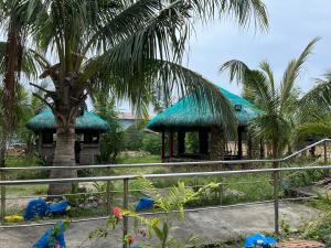 a house with a blue roof with palm trees at Beachside House with 2 bedrooms in Dalumpinas Oeste