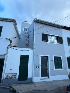 a white building with a green door and windows at Casa Brumar Beach and Downtown on Foot in Praia da Vitória