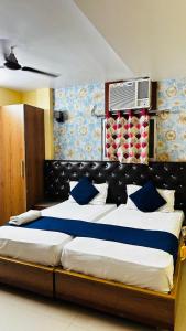 a bedroom with a large bed with blue and white pillows at Hotel Raj Palace in Āzamgarh