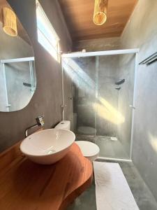 a bathroom with a sink and a glass shower at Villa Fênix Suítes in Barreirinhas