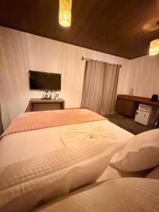 a bedroom with two beds and a tv on the wall at Villa Fênix Suítes in Barreirinhas