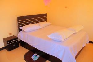 a bedroom with a large bed with white sheets and pillows at Abusera Bishoftu Guest House in Yerer