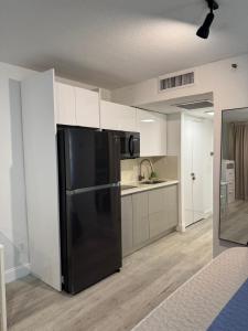 a kitchen with a black refrigerator and white cabinets at Ocean front Condo with balcony on the beach in Sunny Isles Beach