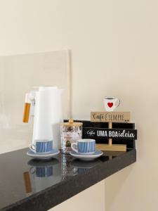 a counter with two cups and plates and a coffee maker at Casa 01 - Completa e moderna 5 minutos do centro in Alta Floresta