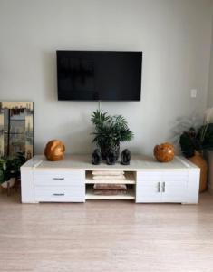 a white entertainment center with a television on a wall at Seaside Escape Rockingham in Rockingham