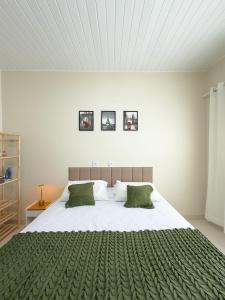 a bedroom with a large white bed with green blankets at Casa 01 - Completa e moderna 5 minutos do centro in Alta Floresta