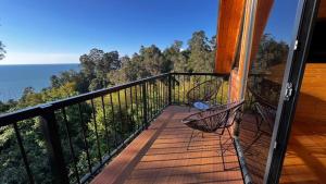 a balcony with two chairs and a view of the ocean at Magnolia Cottage in Ts'ikhisdziri