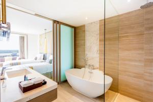 a bathroom with a tub and a sink and a bedroom at Crowne Plaza Vientiane, an IHG Hotel in Vientiane
