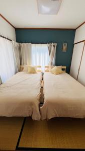 two beds sitting next to each other in a room at IWAKI Stay KAKUREGI in Hirosaki