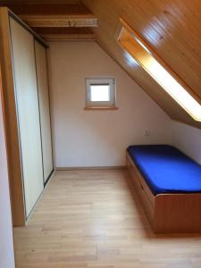 a small room with a blue bed and a window at Chata Miška in Drienica