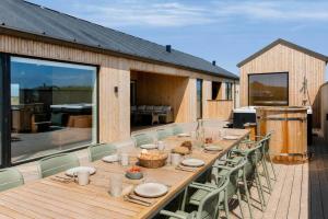 a long wooden table and chairs on a deck at 839-Harboore-Strandvaenget-6 in Harboør