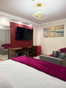 a living room with a bed and a flat screen tv at Pousada Lumiera House in Foz do Iguaçu