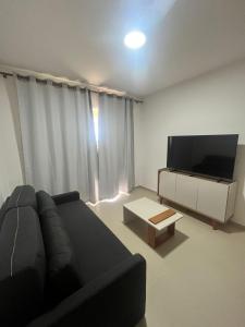 a living room with a black couch and a flat screen tv at Canoa Breeze - Beach Front in Canoa Quebrada