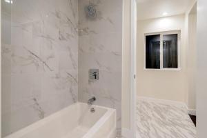 a white bathroom with a tub and a window at Executive Stay Inn free parking in Oakland