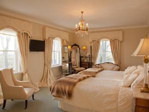 a bedroom with two beds and a chair and a chandelier at West Longridge Manor B&B in Berwick-Upon-Tweed