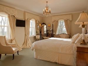 a bedroom with a large white bed and a chair at West Longridge Manor B&B in Berwick-Upon-Tweed