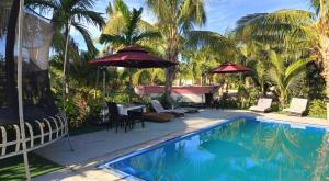 a pool with umbrellas and chairs and a table at Nadi Fancy Hotel in Nadi