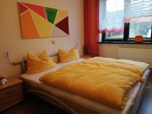 a bedroom with a large bed with yellow sheets and pillows at Pension & Ferienwohnung Eitler in Aue-Bad Schlema