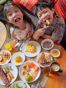 two little girls sitting at a table with plates of food at DoubleTree by Hilton Sukhumvit Bangkok in Bangkok