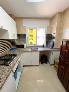 a kitchen with white cabinets and a window at Visit Chamal - Palmera 3 in Oued Laou +8 photos