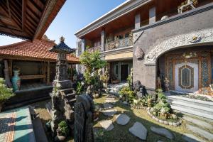 a garden in front of a building with trees and rocks at Puri Mayapada Nusa Dua Bali in Nusa Dua