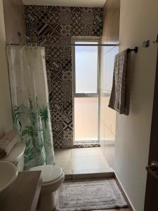 a bathroom with a shower and a toilet and a window at Casa Zaabi in Oaxaca City