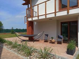 a hammock and two chairs in front of a house at Apartament łeba in Żarnowska