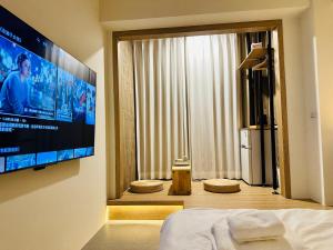 a bedroom with a large flat screen tv on a wall at mini嵐輕旅 in Guanyin