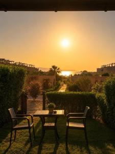 two chairs and a table with a sunset in the background at La Hacienda Ras Sedr in Ras Matarma