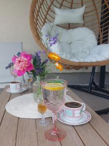 a table with two glasses and a cup of coffee and flowers at 3a kuca Bajevac in Bajevac