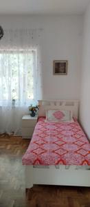 a bedroom with a bed with a red comforter and a window at 3a kuca Bajevac in Bajevac