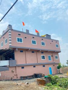 a pink building with two flags on top of it at Hotel Arpita in Ashta