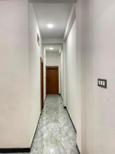 a hallway with white walls and tile floors at Hotel Arpita in Ashta