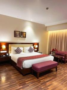a hotel room with a large bed and a purple bench at Peralam Rooms in Peralam Junction